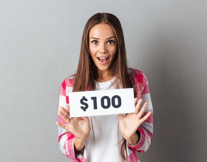 Young woman holding $100 sign
