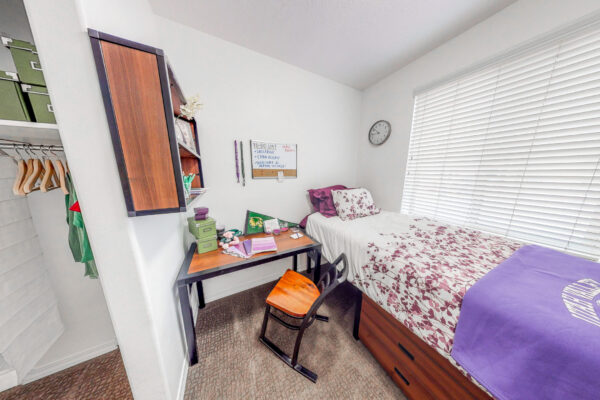 student apartment bedroom with bed, desk, & shelving